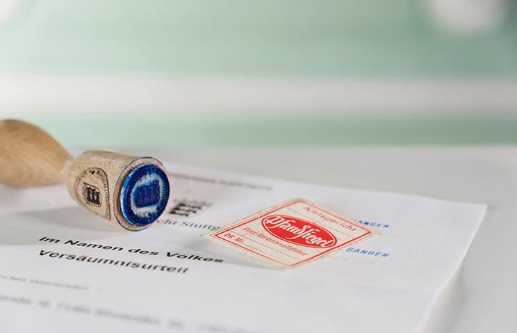 Das Bild zeigt ein Urteil, ein Gerichtssiegel und eine Pfandsiegelmarke