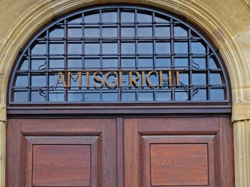 Das Bild zeigt den oberen Teil einer Tür. Über der Tür steht das Wort Amtsgericht.