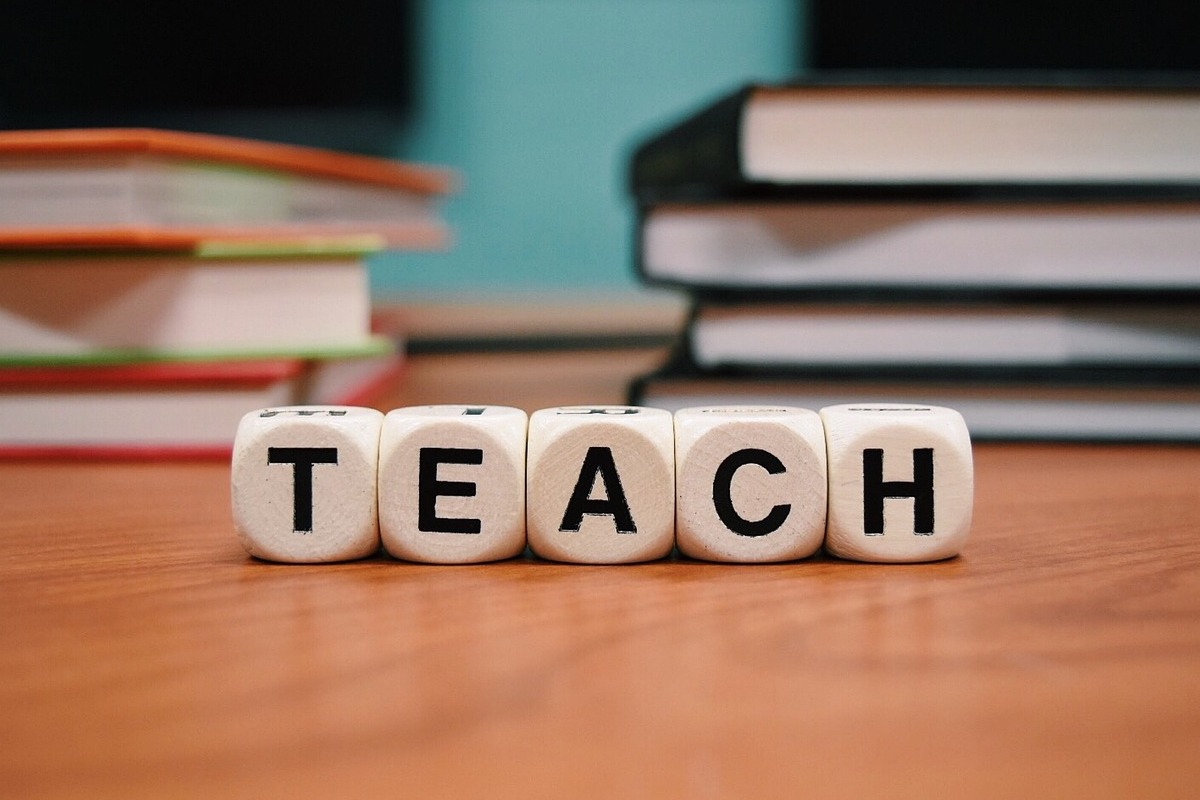 Das Bild zeigt fünf Würfel mit Buchstaben. Sie bilden zusammen das Wort TEACH.