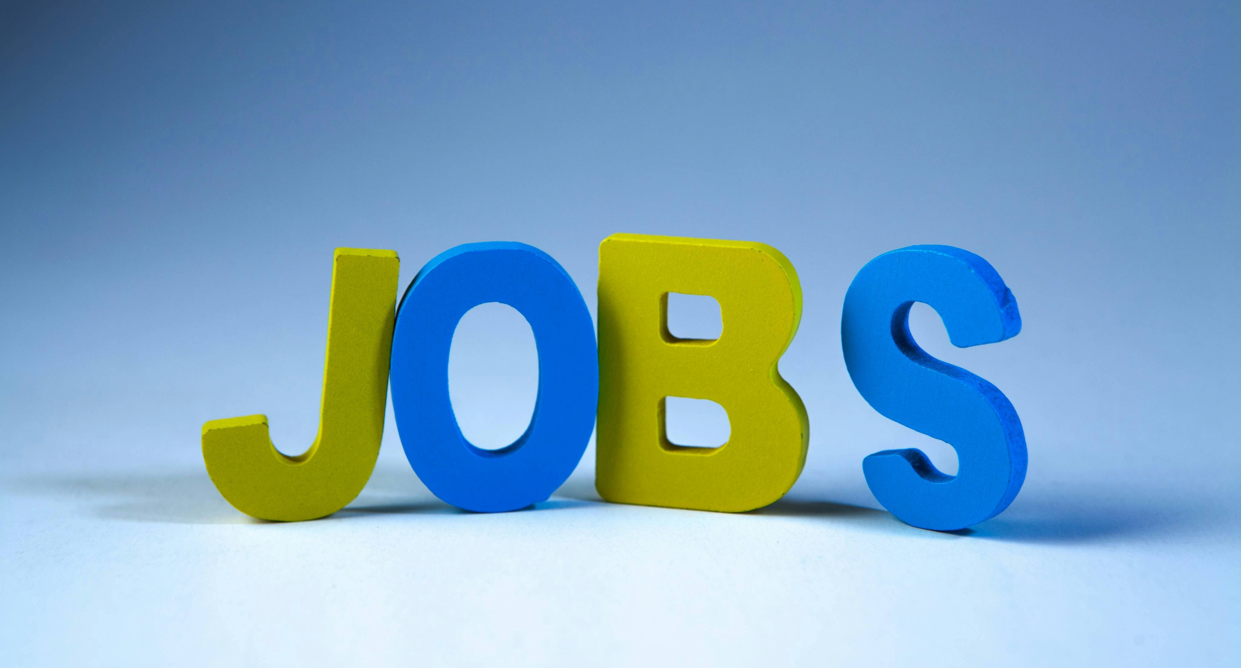 Das Bild zeigt das Wort JOBS in gelben und blauen Buchstaben.