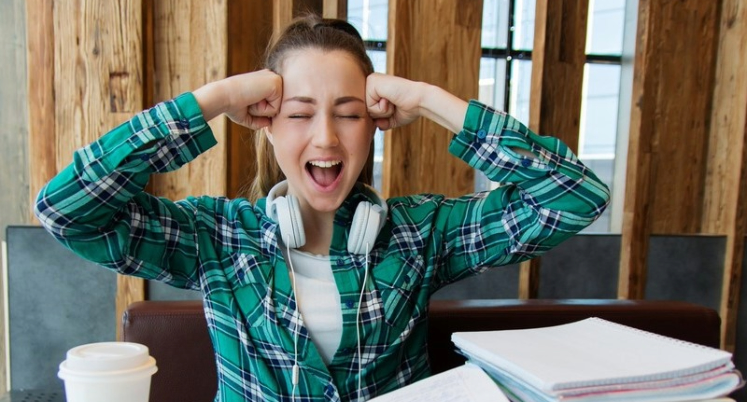 Das Bild zeigt eine Studentin, die vor Büchern sitzt und sich beide Fäuste an die Schläfen drückt.